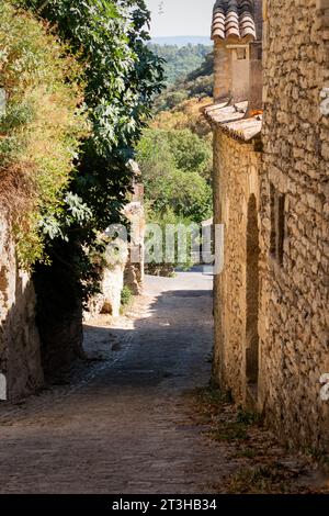 Sommerspaziergang durch die Stadt Gordes auf einer gepflasterten und engen Straße. Stockfoto