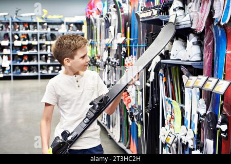 Junge mit Alpinski in einem Sportwarenladen Stockfoto