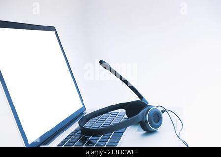 Schwarzes Video-Konferenz-Headset auf einer Computertastatur mit weißem Bildschirm Stockfoto