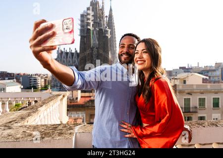 Multirassisch wunderschönes glückliches Paar von Liebhabern, die sich auf dem Dachbalkon in der Sagrada Familia, Barcelona, treffen - multiethnische Leute haben ein romantisches Treffen auf einem Stockfoto