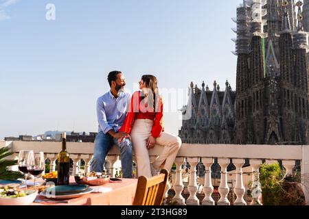 Multirassisch wunderschönes glückliches Paar von Liebhabern, die auf dem Dachbalkon in der Sagrada Familia, Barcelona, ausgehen - multiethnische Leute, die einen romantischen Aperitif genießen Stockfoto