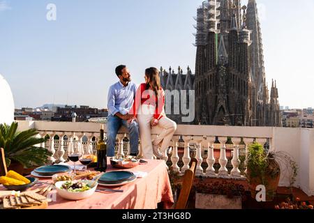Multirassisch wunderschönes glückliches Paar von Liebhabern, die auf dem Dachbalkon in der Sagrada Familia, Barcelona, ausgehen - multiethnische Leute, die einen romantischen Aperitif genießen Stockfoto
