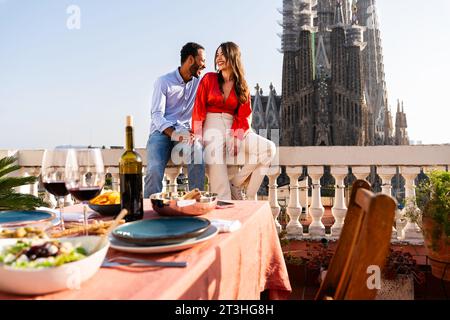 Multirassisch wunderschönes glückliches Paar von Liebhabern, die auf dem Dachbalkon in der Sagrada Familia, Barcelona, ausgehen - multiethnische Leute, die einen romantischen Aperitif genießen Stockfoto