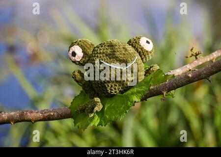 Gestricktes Froschspielzeug im Garten auf einem Baum Stockfoto