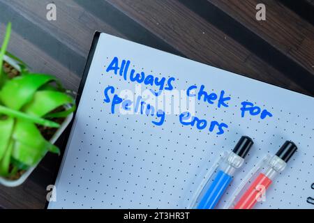 Konzept: Immer auf Rechtschreibfehler prüfen Schreiben Sie auf Buch isoliert auf Holztisch. Stockfoto