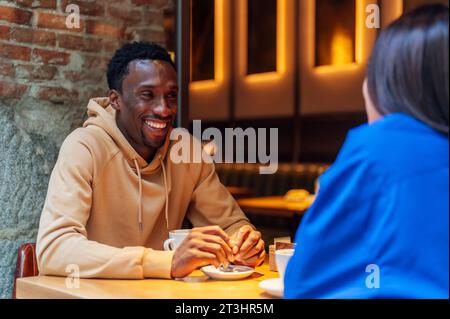 Ein lächelnder afroamerikanischer Junge trinkt Kaffee mit einem Freund Stockfoto