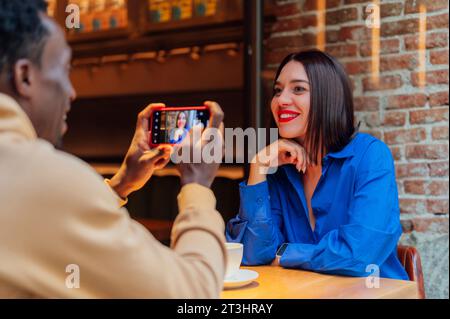 Junger Mann, der Selfie mit seinem Freund macht und Kaffee in einem Café trinkt. Junge Freunde sitzen zusammen im Café und machen Selfie. Stockfoto