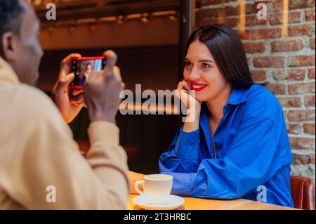 Ein Mann, der einen Freund in einem Café fotografiert Stockfoto