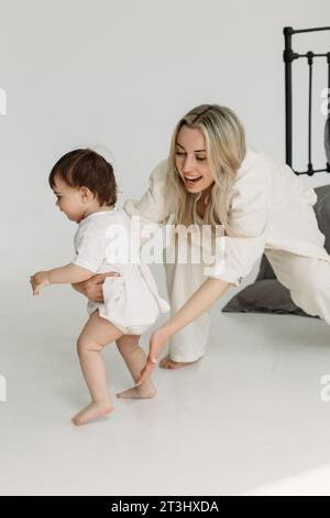 Mom spielt mit ihrer Tochter, holt sie im Zimmer ein, versucht sie zu fangen, lächelt. Zeit Entspannen. Eine glückliche Familie. Stockfoto