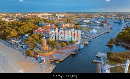 Das Drohnenfoto fängt Kołobrzeg maritimen Charme ein, mit dem berühmten Leuchtturm, dem braunen Meer, turbulenten Wellen und einem entfernten Pier. Stockfoto
