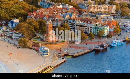Das Drohnenfoto fängt Kołobrzeg maritimen Charme ein, mit dem berühmten Leuchtturm, dem braunen Meer, turbulenten Wellen und einem entfernten Pier. Stockfoto