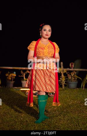 Sundanese Frau, die nach der Tanzvorstellung auf der Bühne ein kurzes Kleid und ein traditionelles gelbes Kleid mit rotem Schal und Make-up trägt Stockfoto