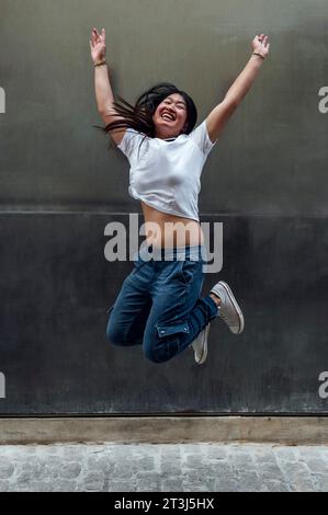 Glückliche asiatische Frau, die auf die Straße springt Stockfoto