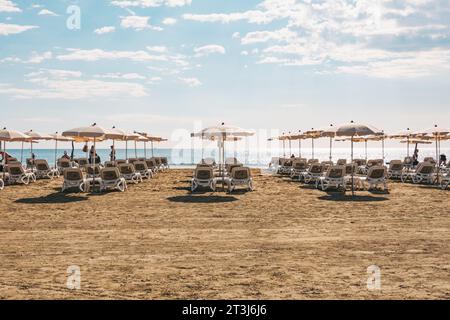 Liegestühle und Sonnenschirme stehen für Kunden am Strand von Finikoudes, Larnaca, Zypern bereit Stockfoto