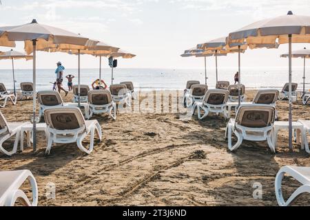 Liegestühle und Sonnenschirme stehen für Kunden am Strand von Finikoudes, Larnaca, Zypern bereit Stockfoto