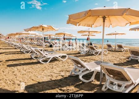 Liegestühle und Sonnenschirme stehen für Kunden am Strand von Finikoudes, Larnaca, Zypern bereit Stockfoto