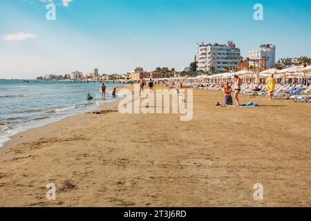 Liegestühle und Sonnenschirme stehen für Kunden am Strand von Finikoudes, Larnaca, Zypern bereit Stockfoto