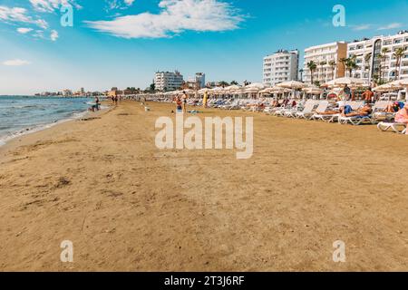 Liegestühle und Sonnenschirme stehen für Kunden am Strand von Finikoudes, Larnaca, Zypern bereit Stockfoto