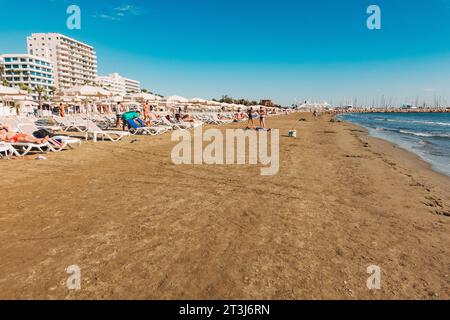 Liegestühle und Sonnenschirme stehen für Kunden am Strand von Finikoudes, Larnaca, Zypern bereit Stockfoto