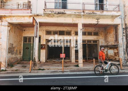 Ein Tourist mit einem Fahrrad durch die verlassene Stadt Varosha, Famagusta, Zypern. Dahinter ist ein leerer Laden zu sehen Stockfoto