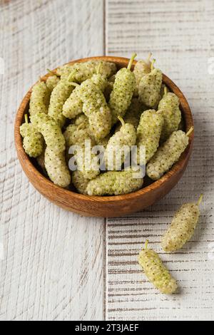 Saftige reife weiße Maulbeeren auf einem Holzteller auf weißem Hintergrund. Beeren, Ernte. Stockfoto