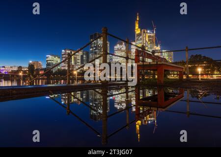 Die leuchtende Frankfurter Skyline am Abend die leuchtende Frankfurter Bankenskyline spiegelte sich am Abend zur Blauen Stunde in einer Regenpfütze am Mainufer. Frankfurt am Main Mainufer Hessen Deutschland *** die strahlende Skyline Frankfurts am Abend spiegelt sich die strahlende Skyline der Frankfurter Bank in einer Regenpfütze am Abend zur blauen Stunde Frankfurt am Main Mainufer Hessen Deutschland 2023-10-25 ffm Skyline 08 Credit: Imago/Alamy Live News Stockfoto