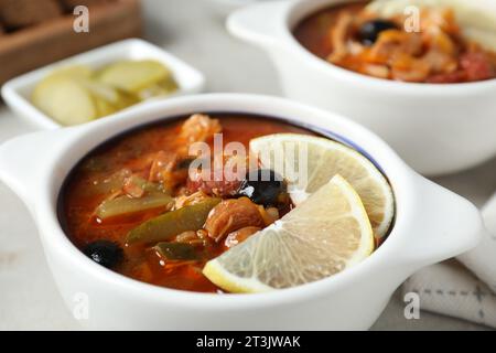 Fleisch-Solyanka-Suppe mit Würstchen, Oliven und Gemüse auf weißem Tisch, Nahaufnahme Stockfoto