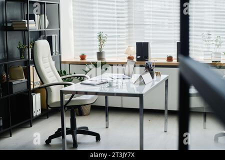 Innenraum des geräumigen Büros des Geschäftsführers oder Unternehmens mit Schreibtisch und komfortablem Ledersessel in der Mitte Stockfoto