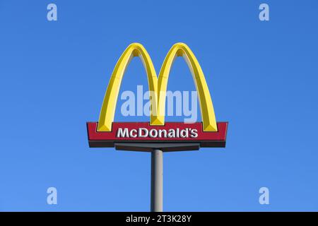 Ellensburg, WA, USA - 20. Oktober 2023; erhöhtes Schild mit goldenen Bögen von McDonald's, dessen Name vor blauem Himmel isoliert ist Stockfoto