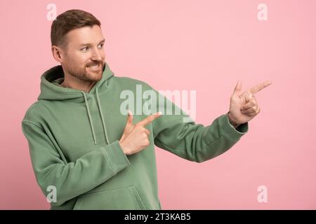 Freundlicher, fröhlicher, unrasierter Mann mittleren Alters, der spielerisch mit den Fingern angenehm lächelt Stockfoto