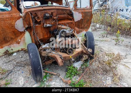 Ein altes, rostiges Auto, bei dem viele Teile entfernt wurden, einschließlich der vorderen Motorhaube und des Motors Stockfoto