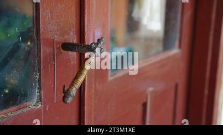 Ein alter Türknauf an einer braunen Tür mit staubigem Glas. Stockfoto