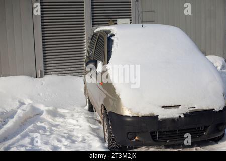 Auto im Winter auf dem Parkplatz. Das Auto im Schnee. Transport unter einer Schneeschicht an einem kalten Tag. Verschneite Straßen. Stockfoto