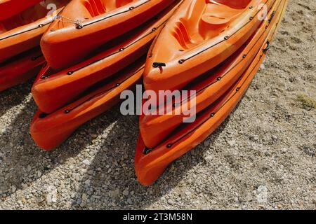 Farbenfrohe orangene Kajaks an einem Sandstrand an sonnigen Tagen. Selektiver Fokus. Stockfoto