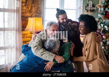 Fröhliche, erweiterte, multiethnische Familie, die Spaß hat, während sie gemeinsam zu Hause Weihnachten feiern. Stockfoto
