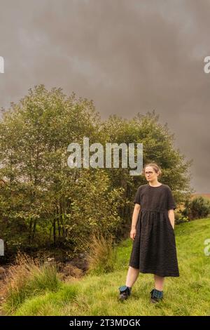 solomädchen in schwarzem Kleid und Brille, die an einigen Büschen in Osmotherly, North Yorkshire, England, Großbritannien steht Stockfoto