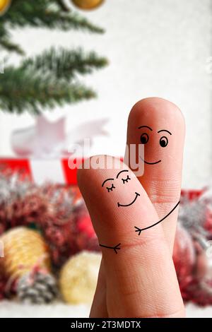 Gesichter von Fingern, die sich gegenseitig umarmen, isoliert auf weihnachtlich dekoriertem Hintergrund. Fröhliche Familie feiert Weihnachtsfeiertag-Konzept Stockfoto