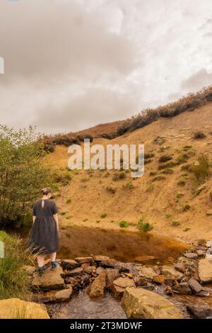 solomädchen in schwarzem Kleid an einem Moorbach unter einer Klippe in Osmotherly, North Yorkshire, England, Großbritannien Stockfoto