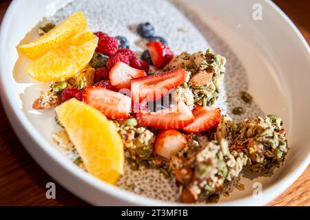 Chia-Pudding mit hausgemachtem Kokosnussgranola, Erdnussbutter und Beeren in einer grauen Schüssel. Gesunde pflanzliche Ernährung, Entgiftung, Sommerrezept. Frühstück im Stockfoto