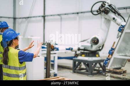 Arbeitnehmerin mit futuristischer Augmented-Reality-Brille in einer Roboterfabrik bei der Arbeit mit KI-Maschinen – Industrie- und Technologiekonzept – F Stockfoto