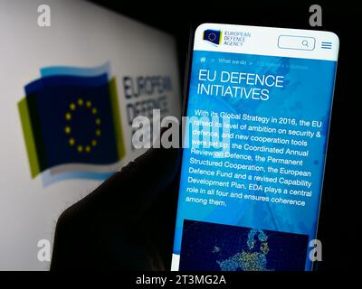 Person, die ein Mobiltelefon hält, mit der Webseite der Europäischen Verteidigungsagentur (EDA) des EU-Organs vor dem Logo. Konzentrieren Sie sich auf die Mitte des Telefondisplays. Stockfoto