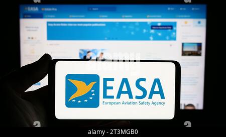 Person, die ein Smartphone mit dem Logo der Agentur der Europäischen Union für Flugsicherheit (EASA) vor der Website hält. Schwerpunkt auf dem Display des Telefons. Stockfoto