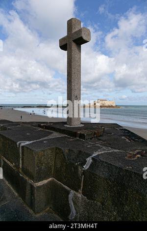 Blick auf den Strand von Saint-Malo vom Hauptmauerwall aus, mit einem steinernen christlichen Kreuz im Vordergrund Stockfoto