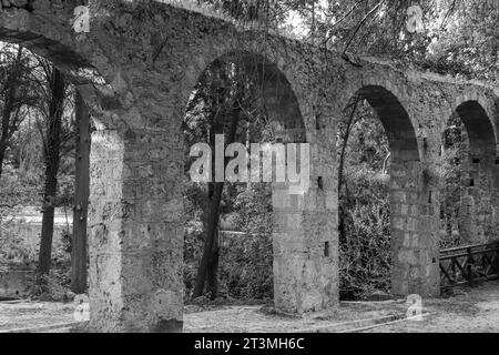 Aquädukt, ein Wasserkursbogen über dem Rodini Park See und Wanderweg im Zentrum von Rhodos. Schwarz-weiß Stockfoto