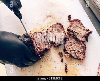 Küchenchef handgeschnittenes Grillsteak im Küchenrestaurant. Der Chefkoch händigt Fleisch aus der Nähe. Professionelles Schneiden von Grillfleisch am Schneidebrett. Stockfoto