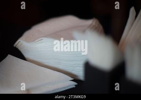 Servietten auf dem Tisch. Weiße Servietten in schwarzem Ständer. Papier Essen. Schwarzer Ständer. Stockfoto