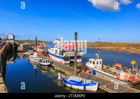 Eine Mischung aus farbenfrohen Freizeit- und Fischerbooten liegt am Steg am Gezeitenkanal in Wells-Next-the-Sea, Norfolk, England, Großbritannien Stockfoto