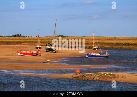 Ebbe für die farbenfrohen Boote auf den Salzwiesen in Wells-Next-the-Sea, Norfolk, England, Großbritannien Stockfoto