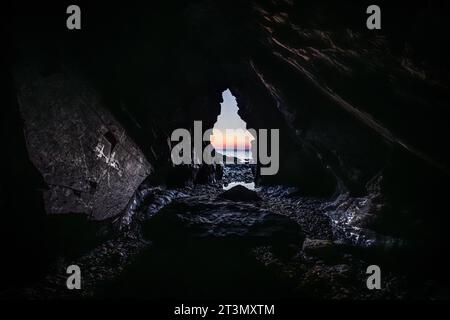 Blick aus einer Höhle auf das Meer mit Sonnenuntergang, auf der Halbinsel Crozon, Bretagne Frankreich Stockfoto