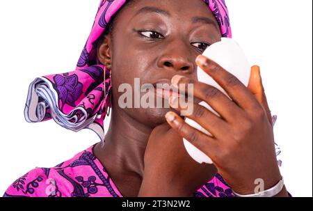 Porträt einer schönen jungen Frau, die ihr Gesicht mit einem Spiegel schminkt. Stockfoto